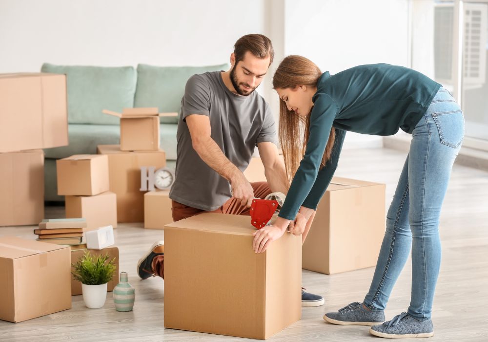 Couple packing cardboard boxes for a move to New Zealand